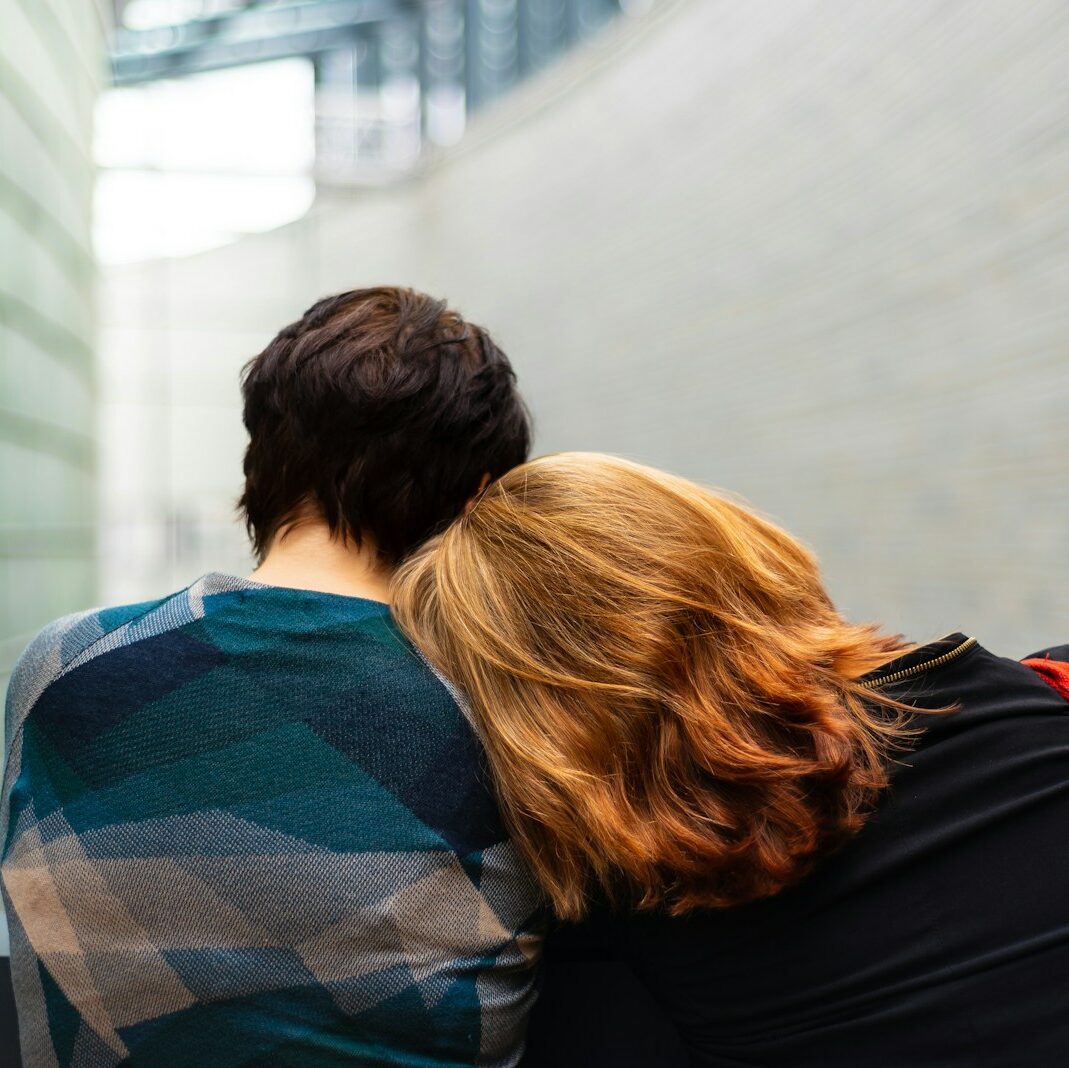 a woman rests her head on another person's shoulder